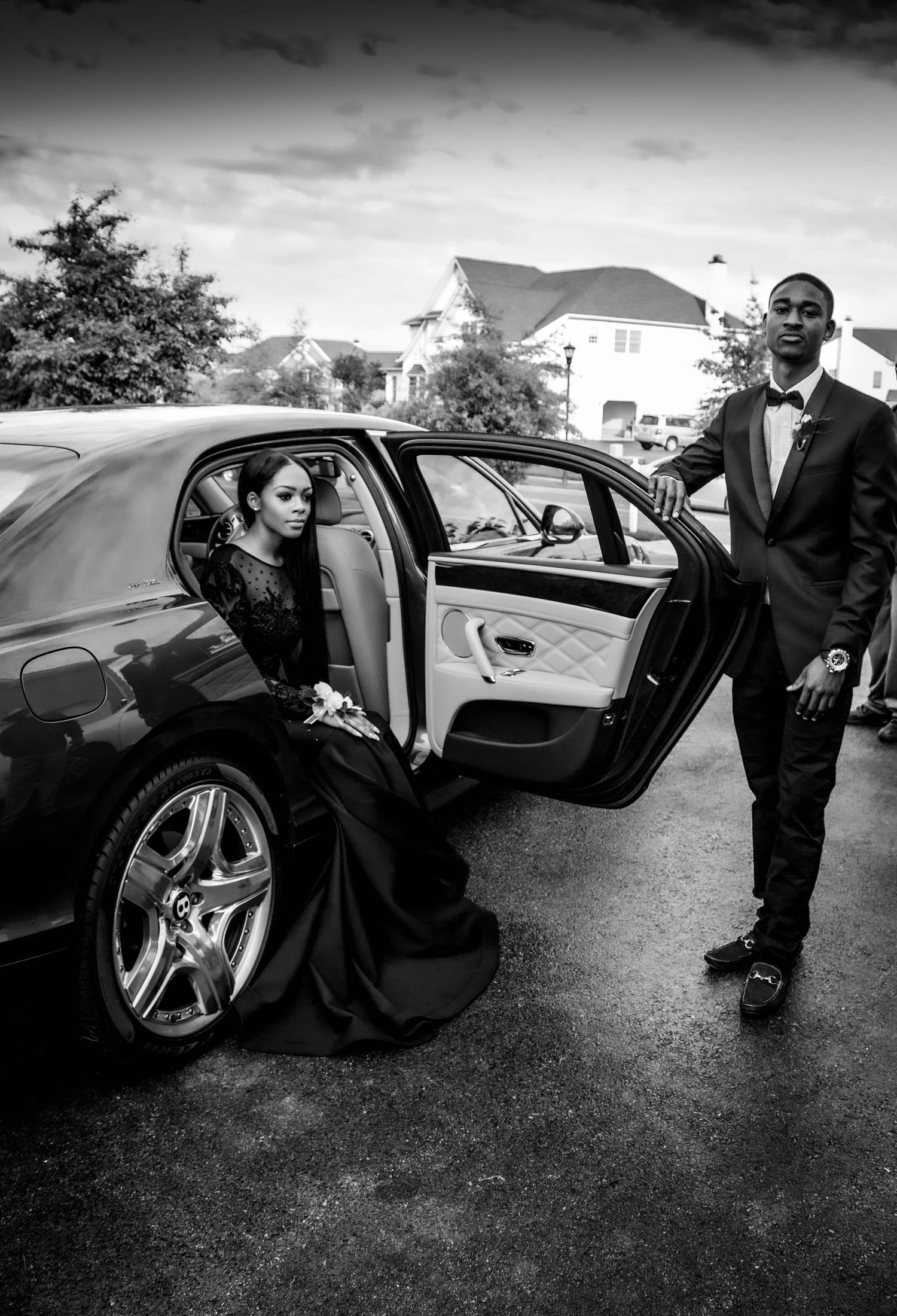 Couple around an elegant black car outdoors. Lifestyle photoshoot. L. Visions Photography. Prom photoshoot. Black and white photo
