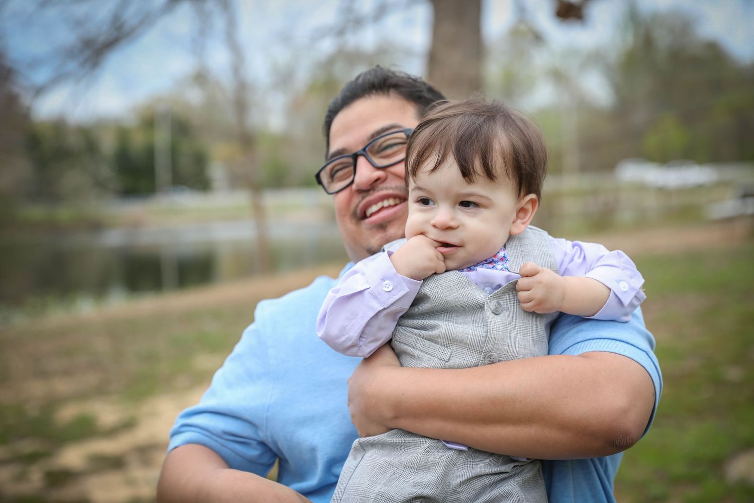 A family shares affectionate moments together during a springtime photo session. Family photoshoot. L. Visions Photography. Father and son.