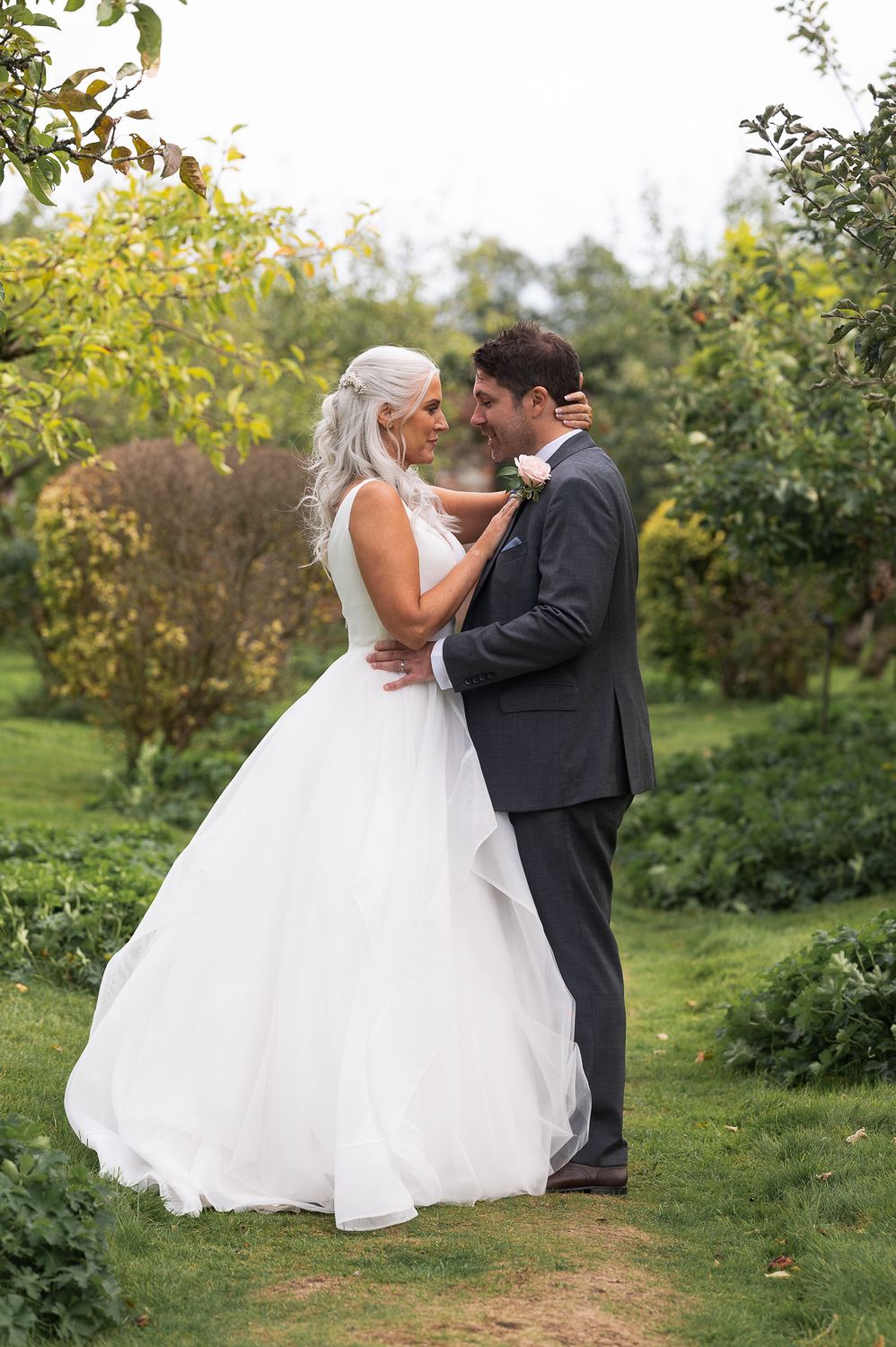 Intimate moment between newlyweds in garden setting surrounded by autumn foliage.