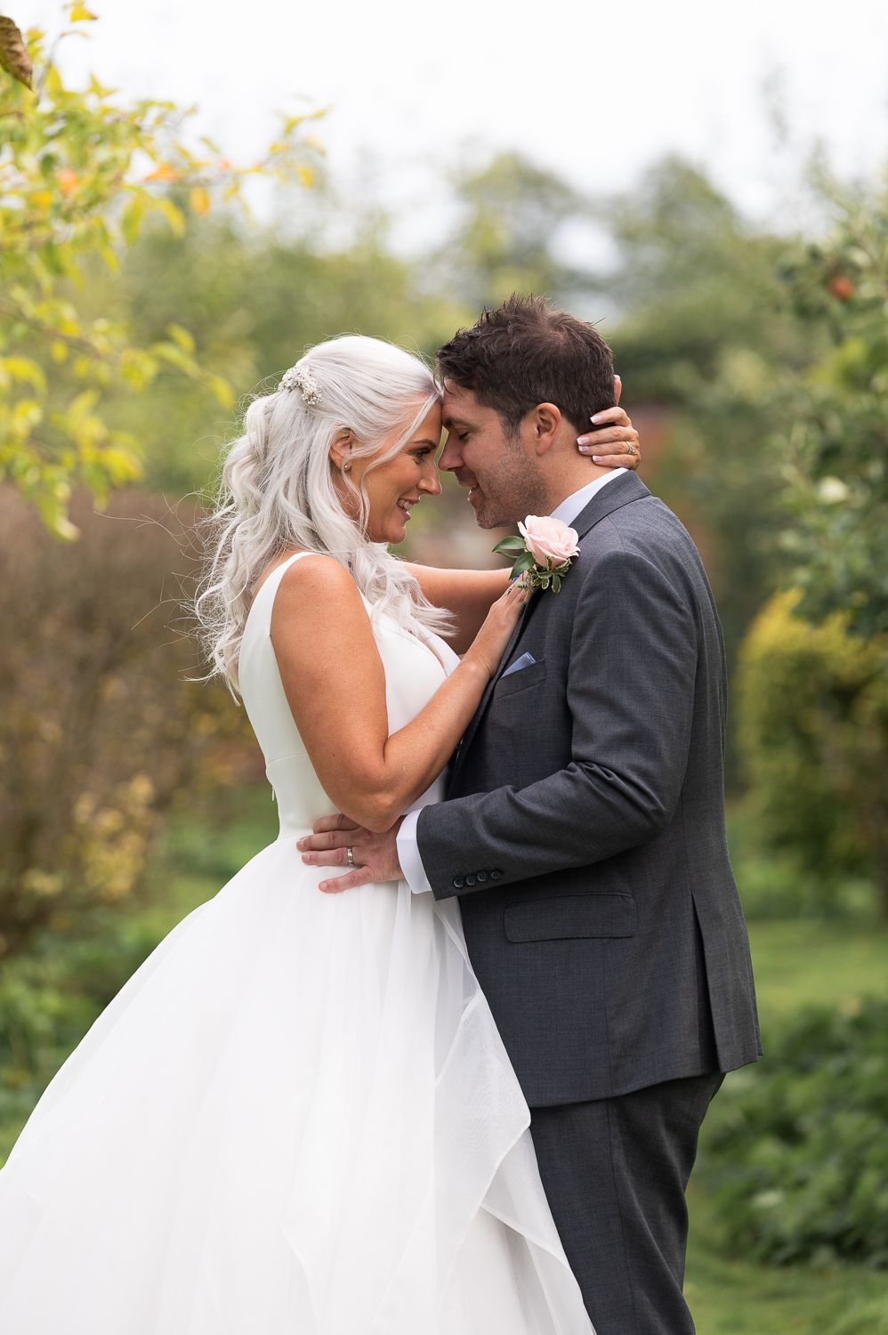 Tender embrace between newlyweds during garden photo session.