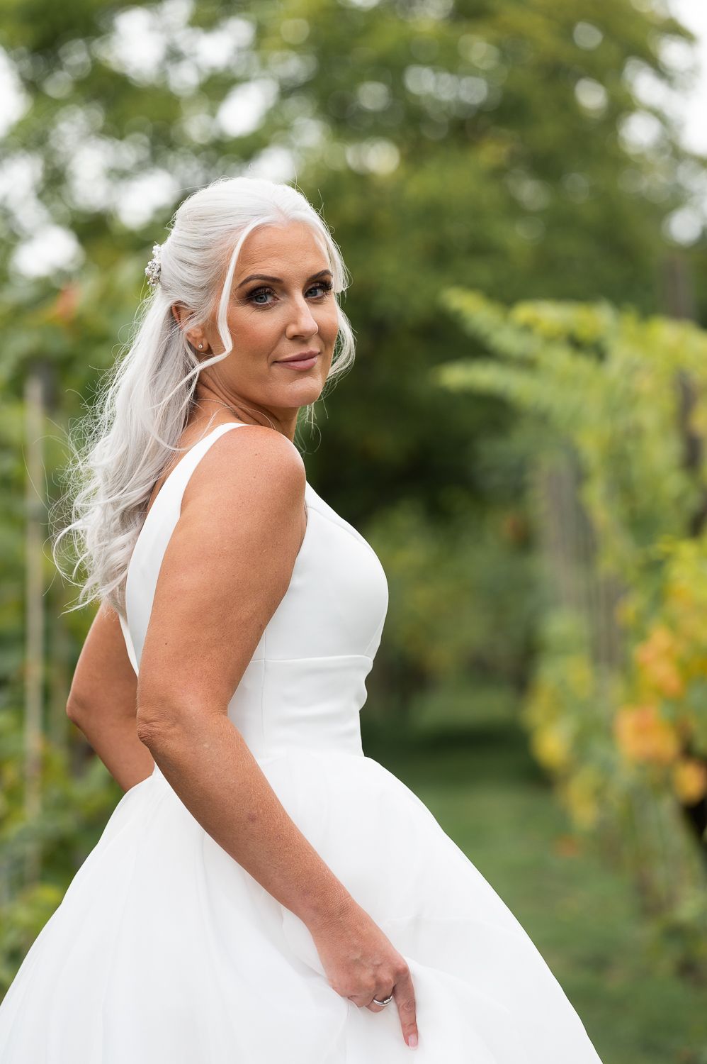 A bride in a flowing white ballgown dress poses in a garden setting with soft natural lighting.