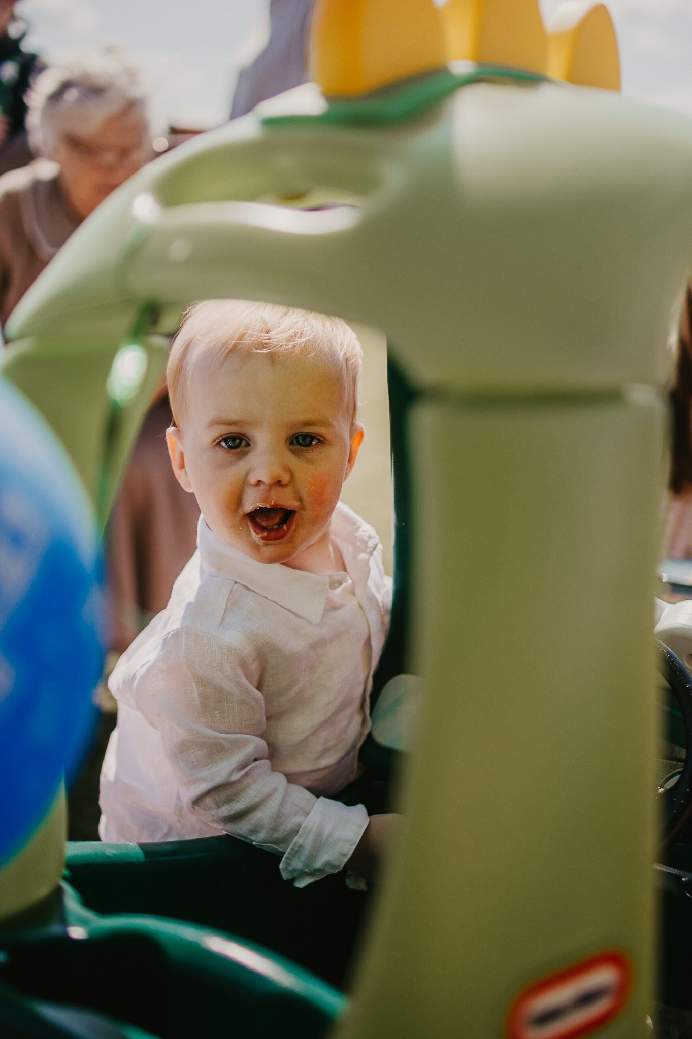 One year old excited birthday boy looking at the camera on his birthday party near his toy car