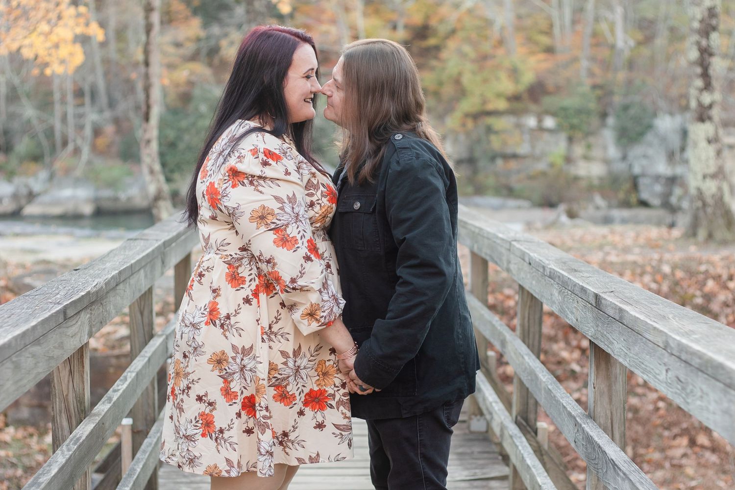 Romantic engagement photos taken on a wooden bridge during fall season.