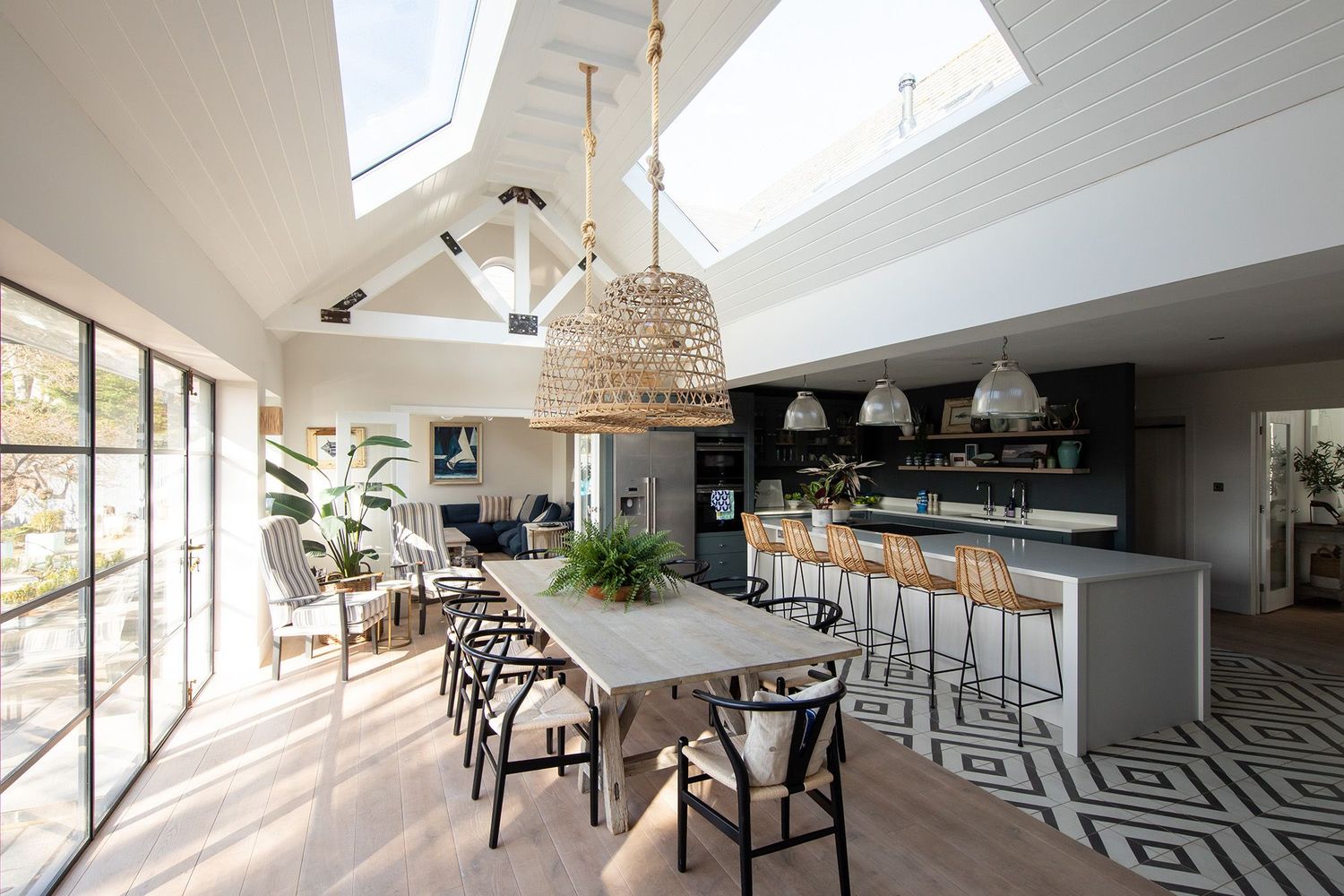 Bright open-concept dining area with woven pendant lights, geometric floor tiles, and floor-to-ceiling windows.