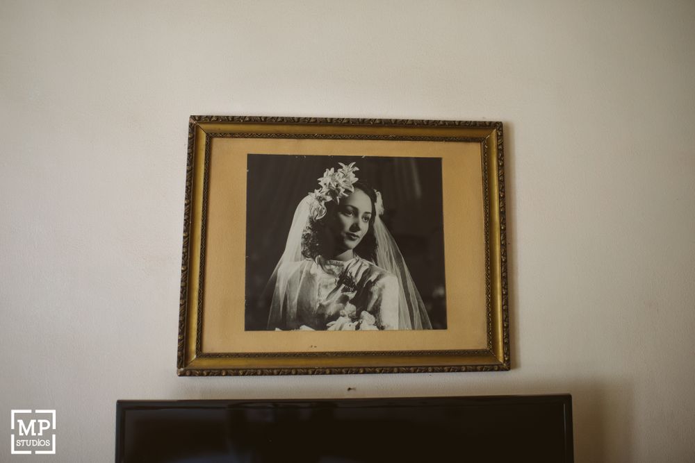 Vintage wedding portrait in ornate gold frame hanging on wall.