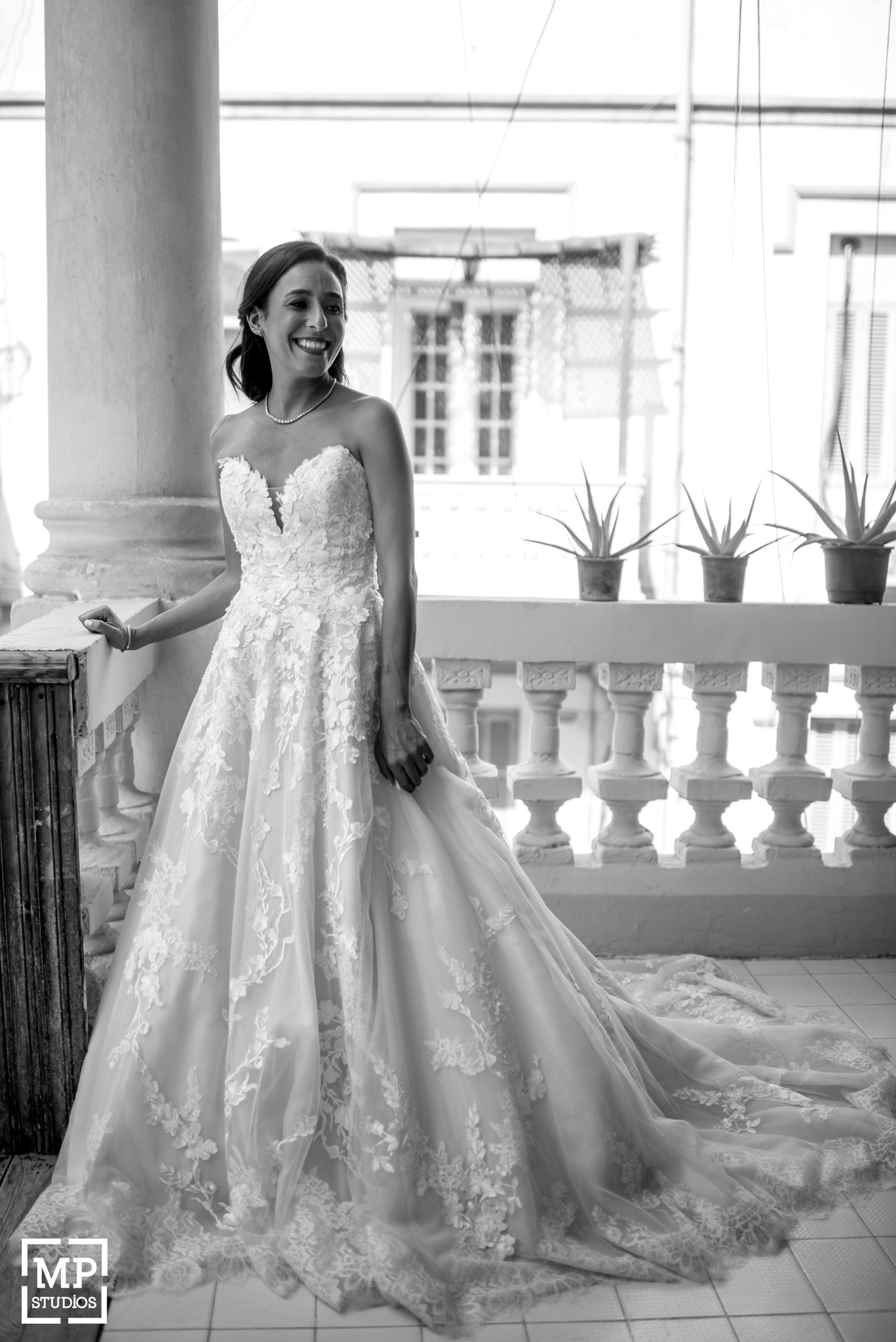 Elegant bridal portrait on a classic balcony with ornate white railings and architectural details.