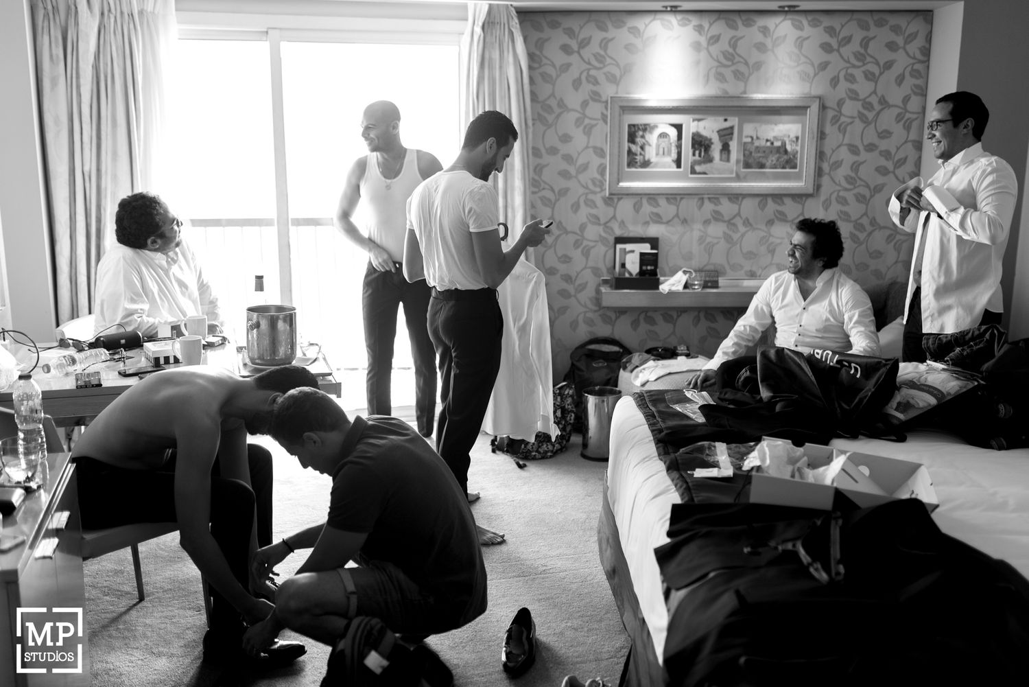Groomsmen getting ready in a hotel room before wedding ceremony.