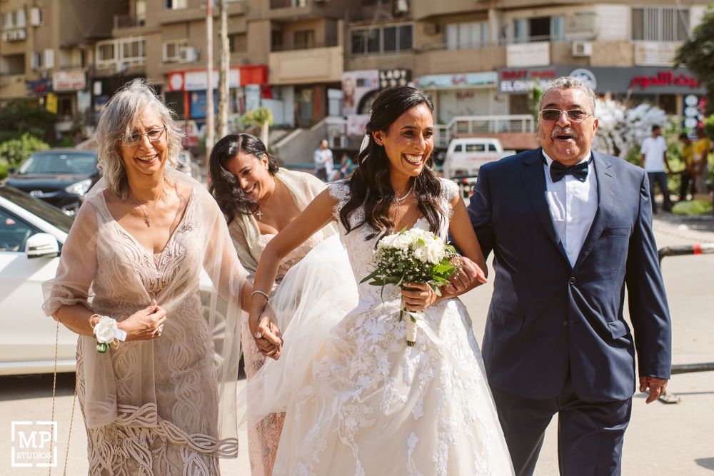 Wedding party walks joyfully down sunny street.