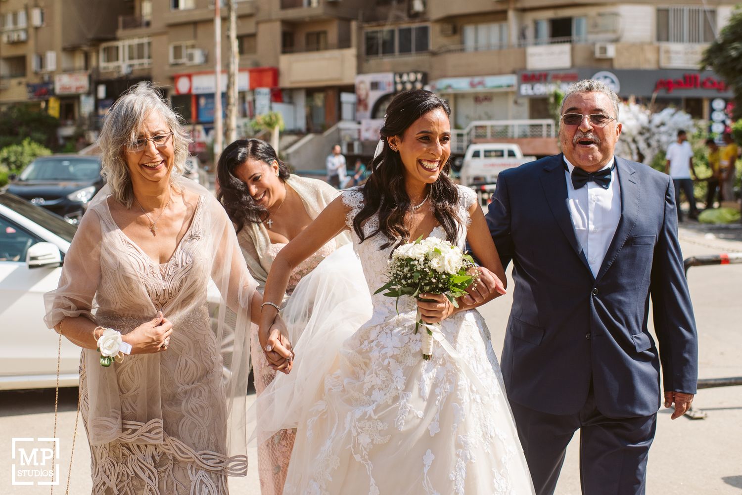 Wedding party walks joyfully down sunny street.