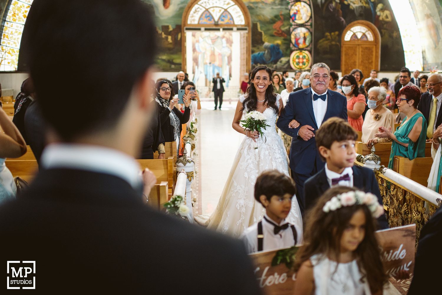 Wedding ceremony in ornate church with decorated aisle and guests.