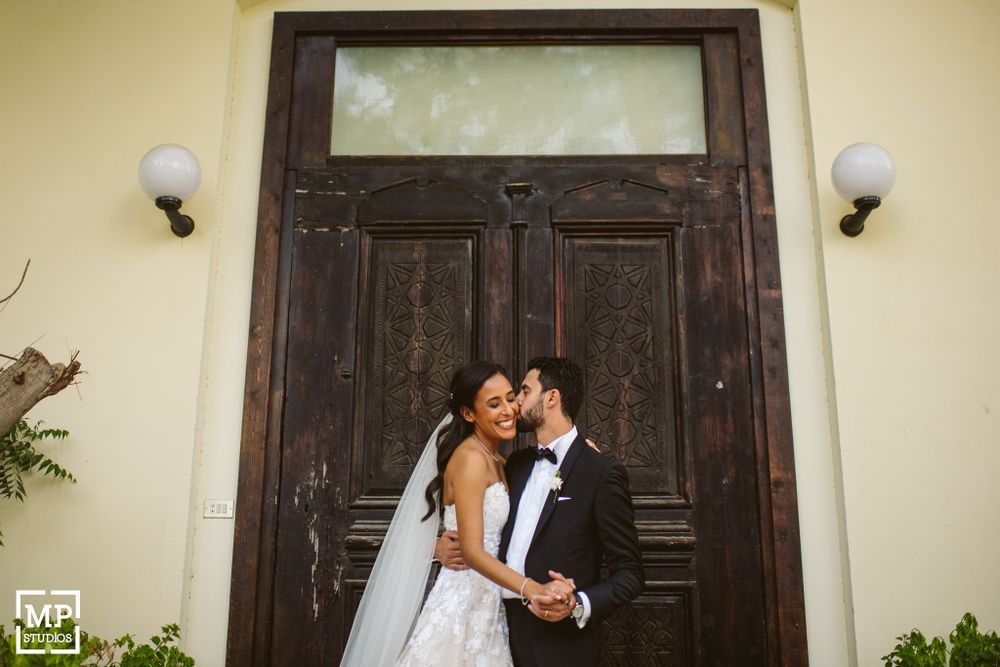 Romantic wedding portrait in front of vintage wooden door with ornate architectural details.