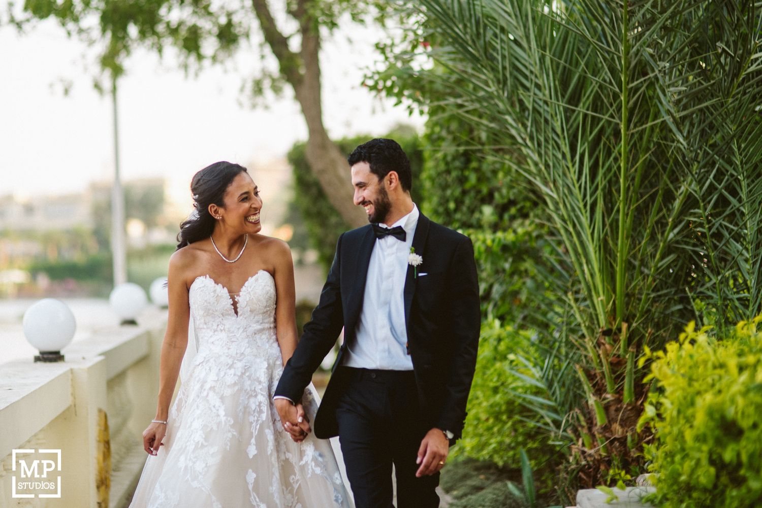 Romantic garden wedding portrait featuring elegant white dress and classic black tuxedo.