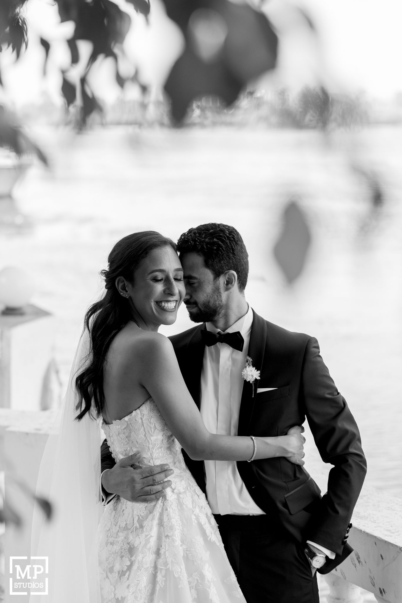 Black and white wedding portrait capturing a joyful candid moment outdoors.