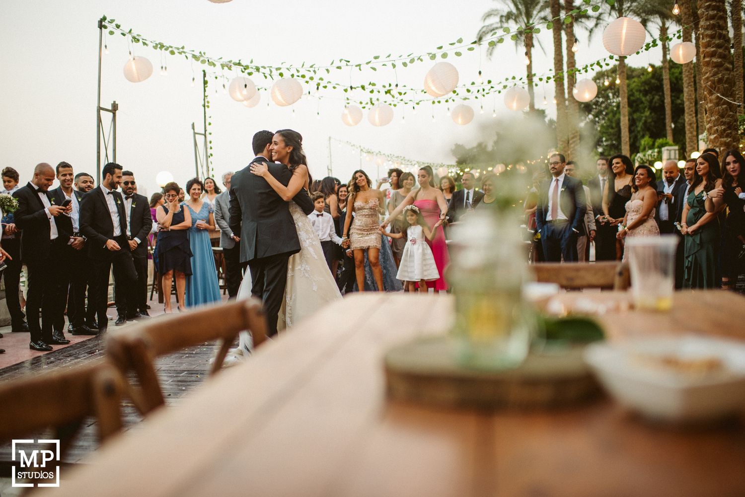 Outdoor evening wedding reception with string lights and decorative table settings.