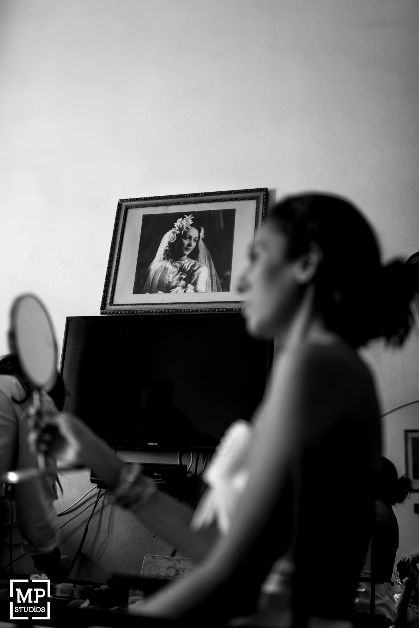 Black and white photograph of a mirror reflection during wedding preparations.