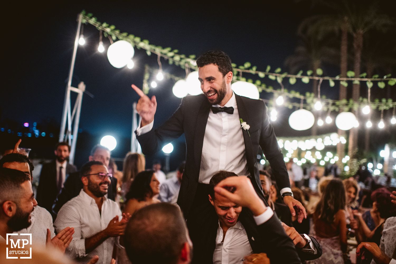 Celebratory moment as reception guests lift someone during an energetic dance party.