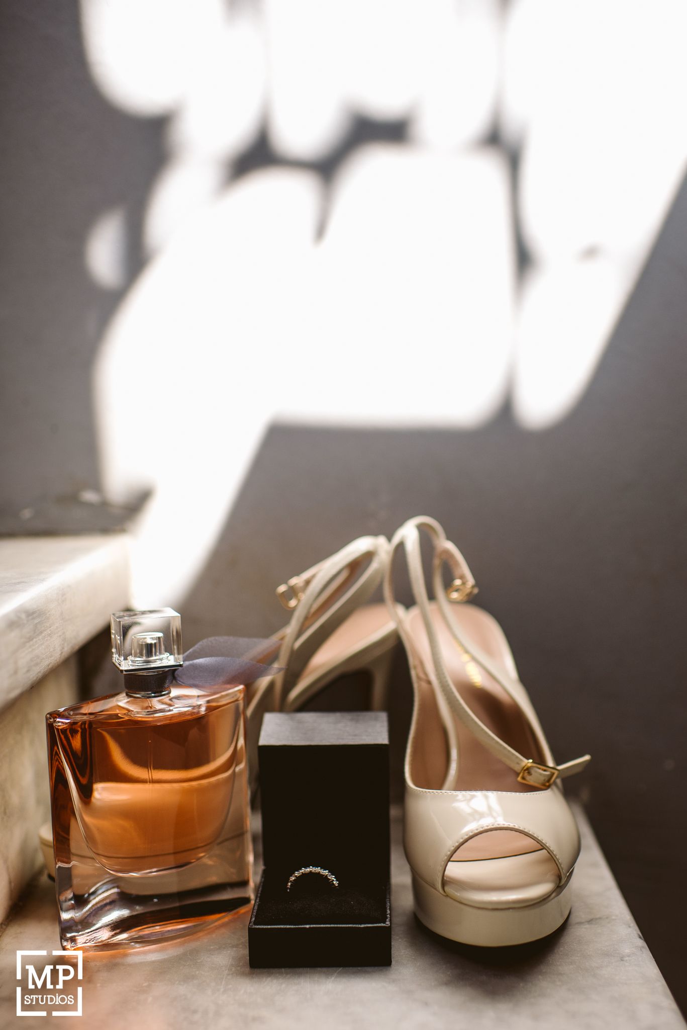 Wedding accessories including perfume bottle, jewelry box and cream colored peep-toe heels.