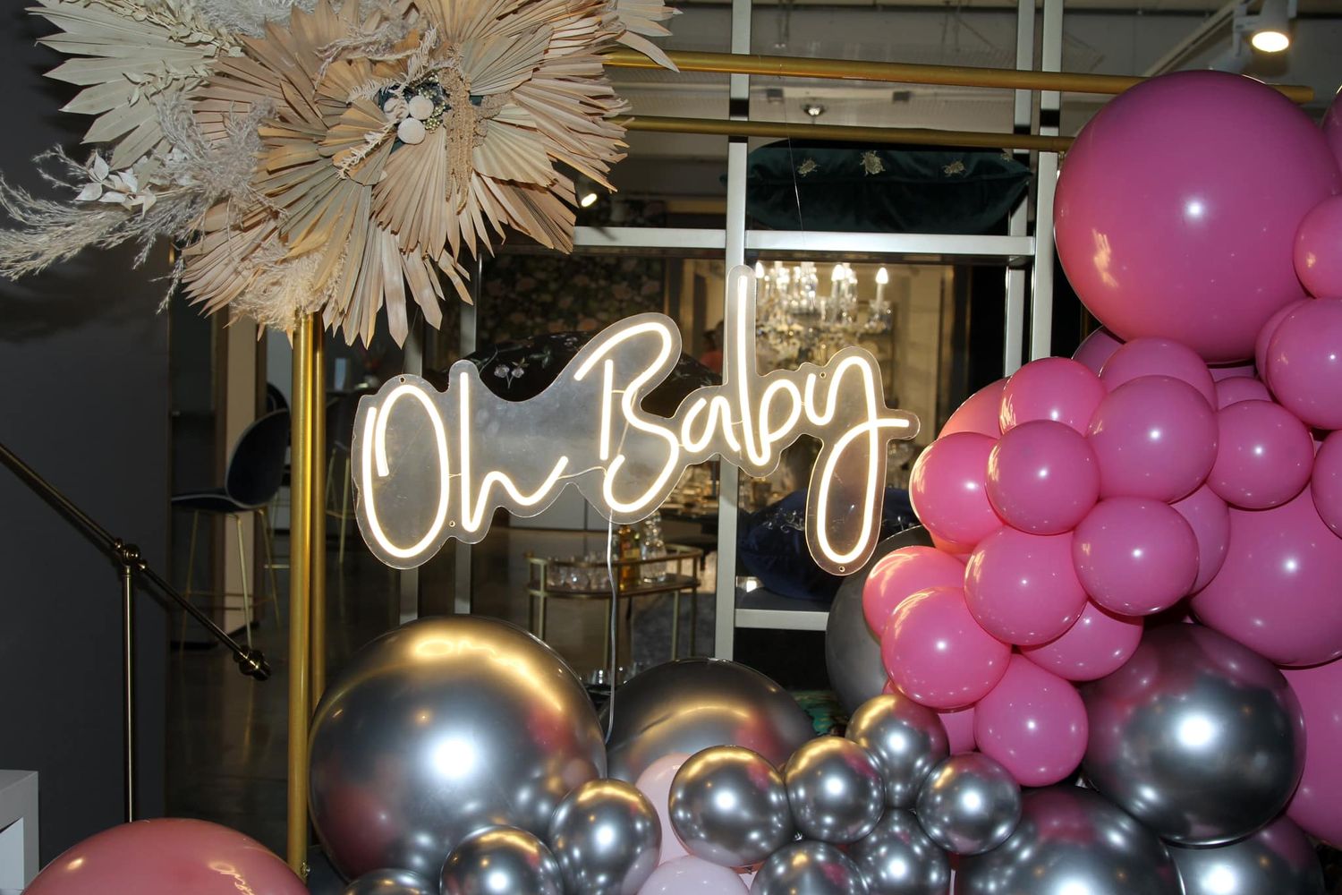 Pink and silver balloon decorations adorn a festive party space with illuminated signage.