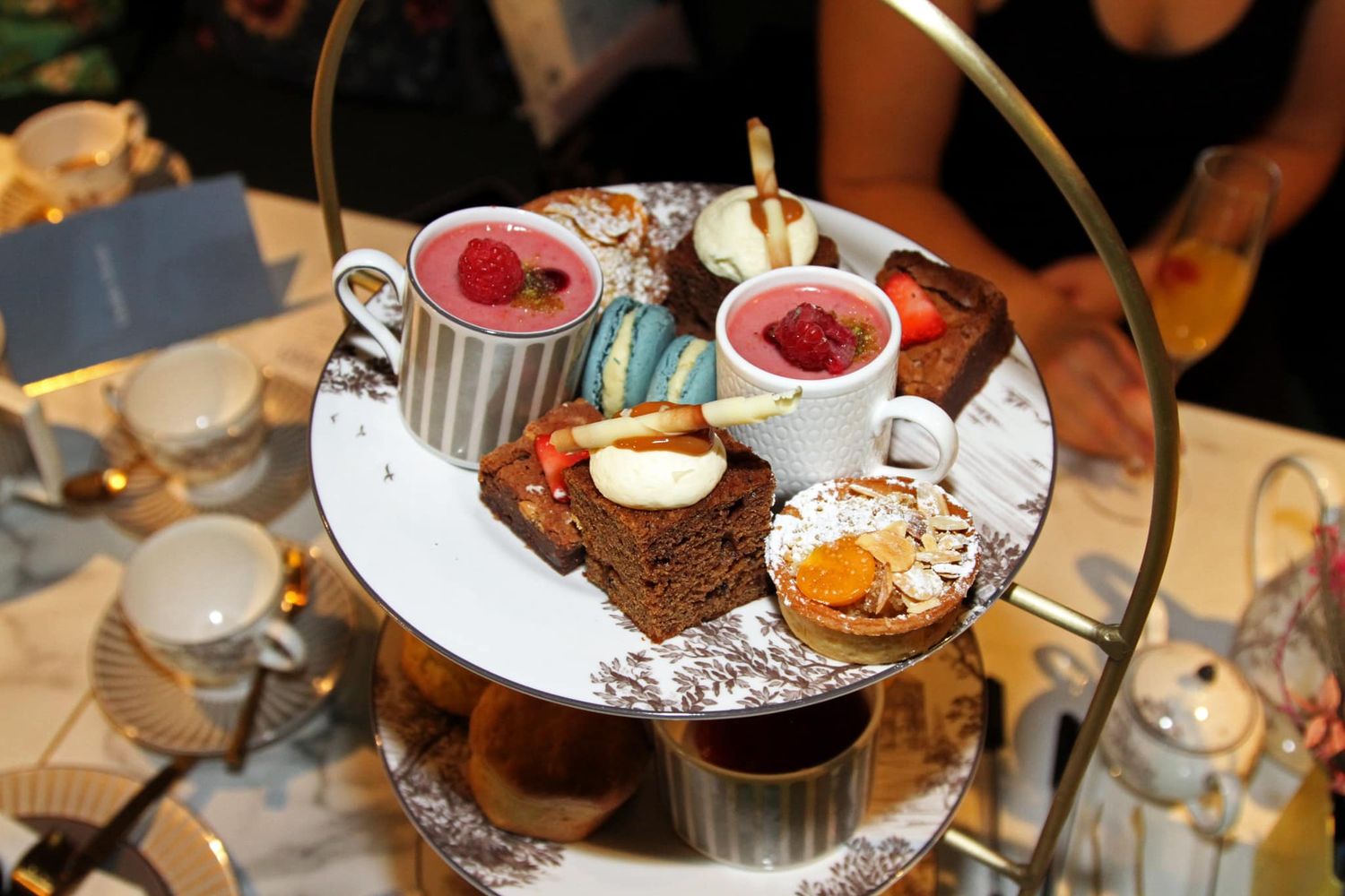 Elegant tiered serving platter with assorted pastries and desserts at an afternoon tea party.