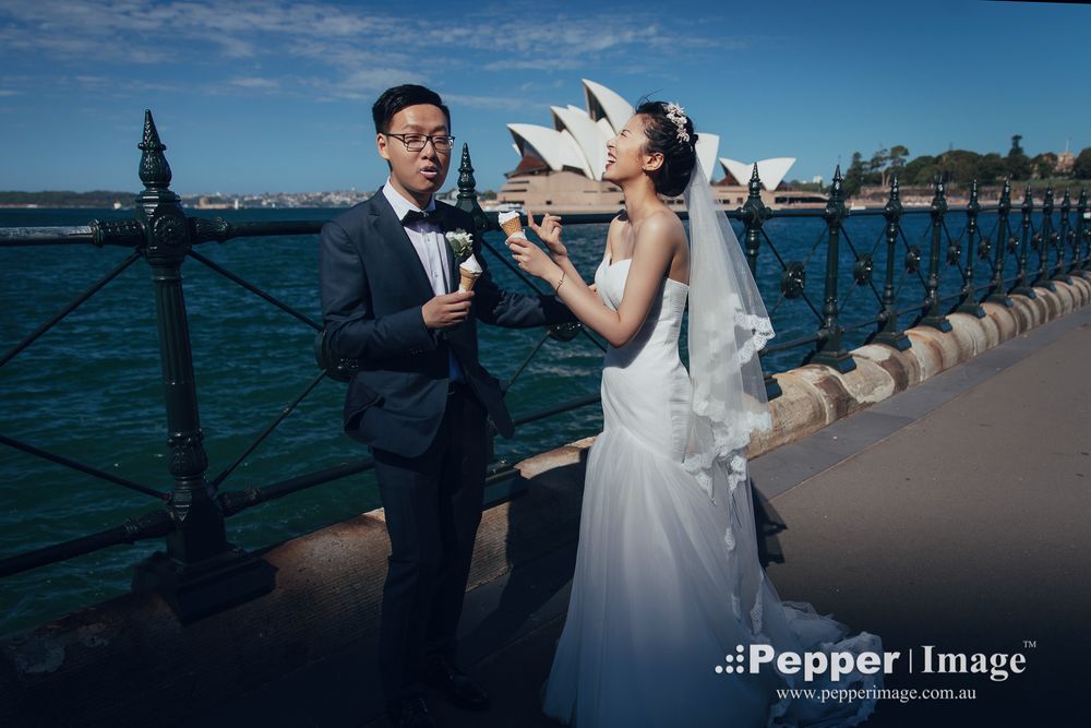 Bride and groom posing near Sydney Opera House waterfront fence on their wedding day.