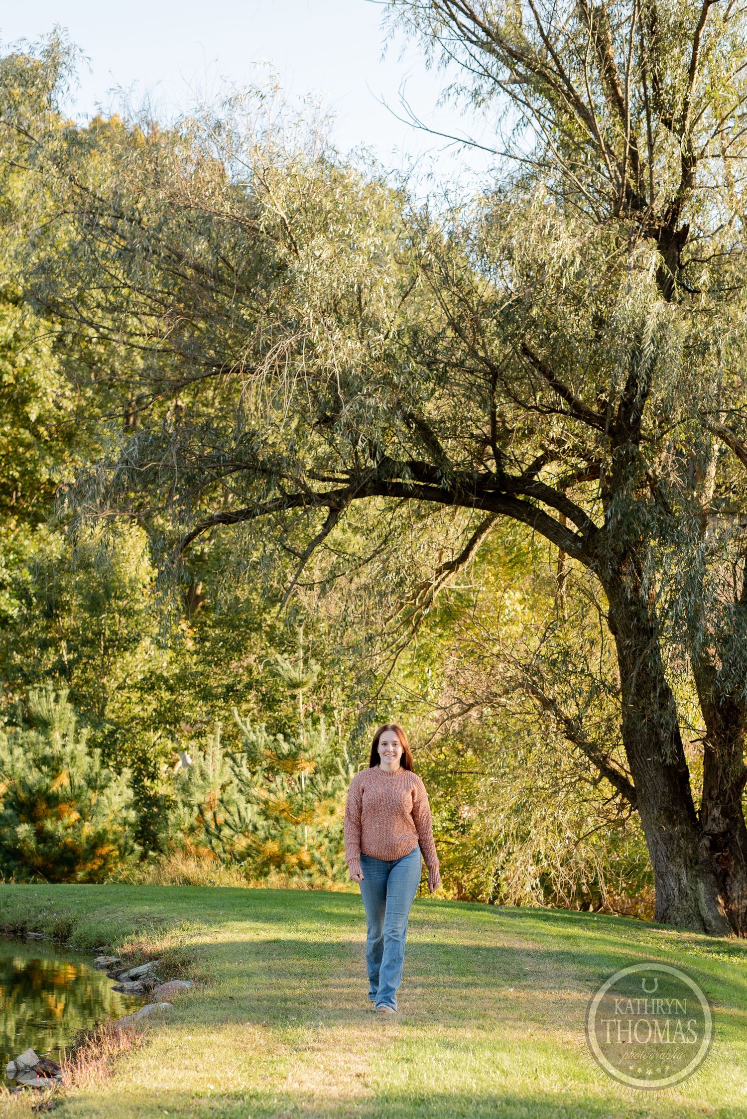 Person in pink sweater strolls along peaceful garden path under arching tree branches.
