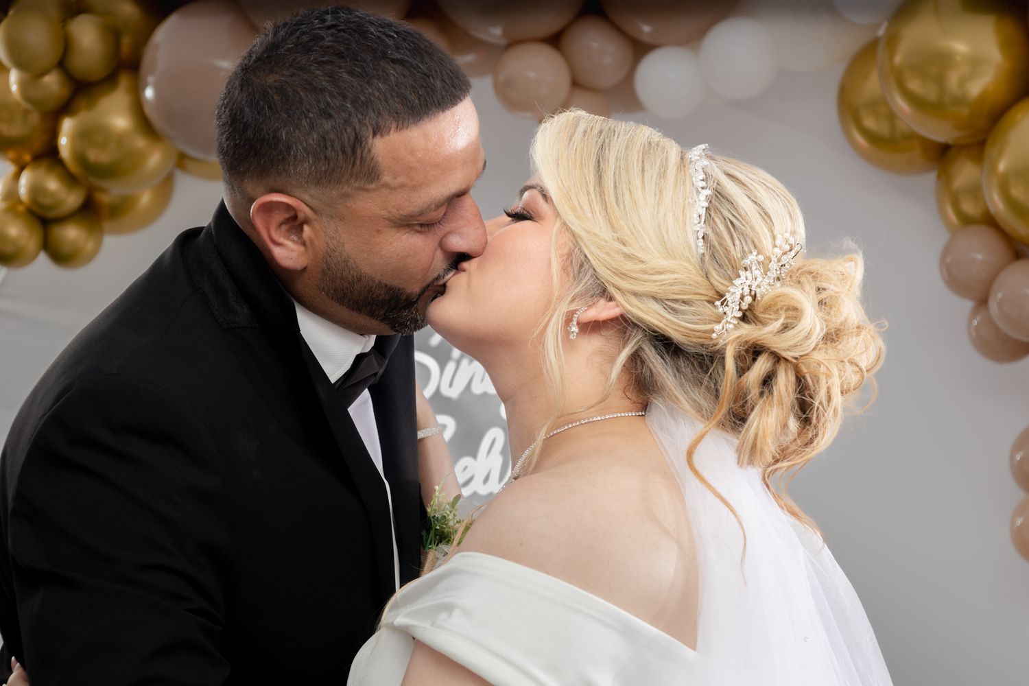 Elegant wedding celebration with gold balloon decorations in the background.
