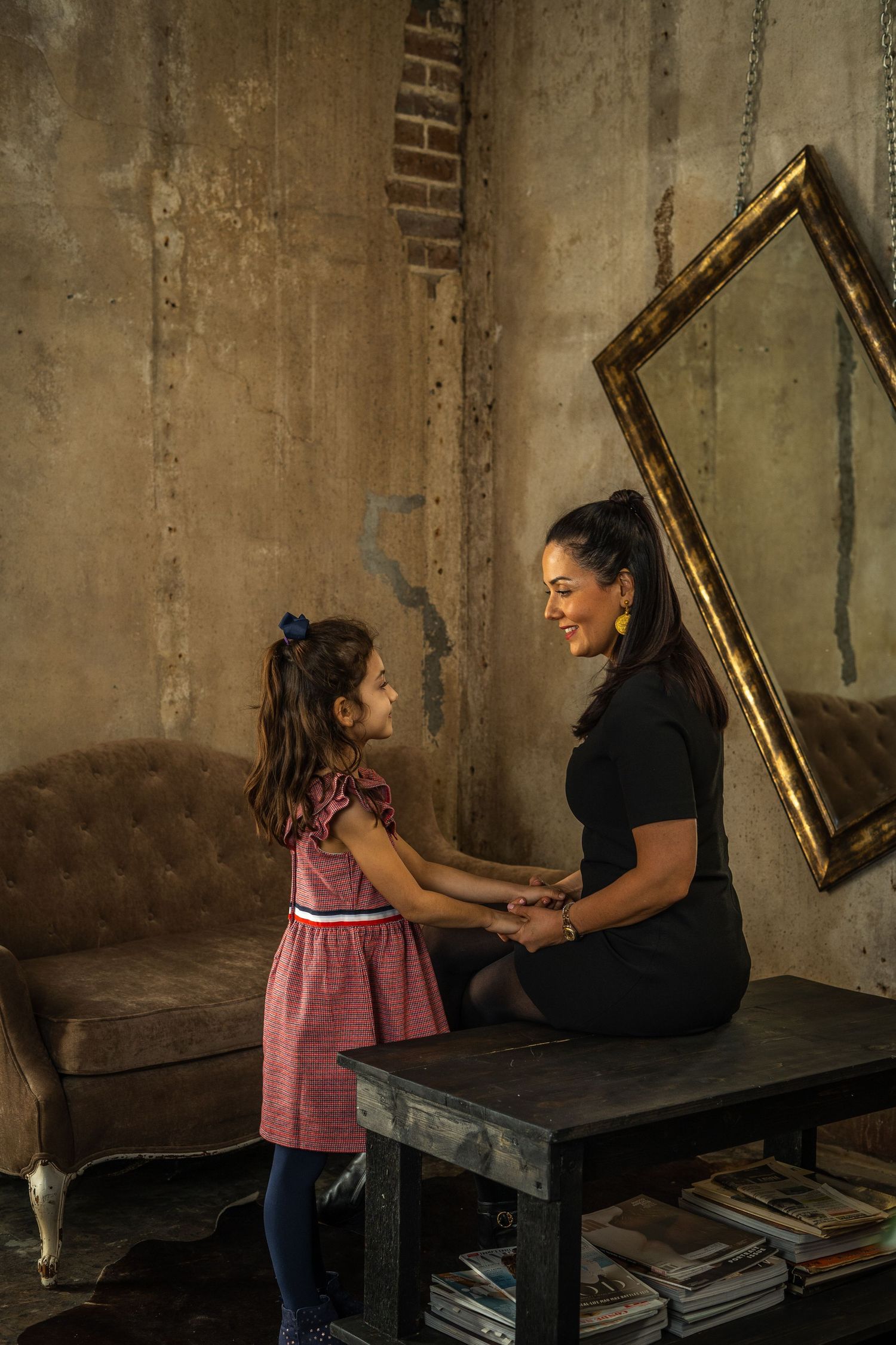 Mother and daughter sharing a tender moment in a vintage room with gold-framed mirror.