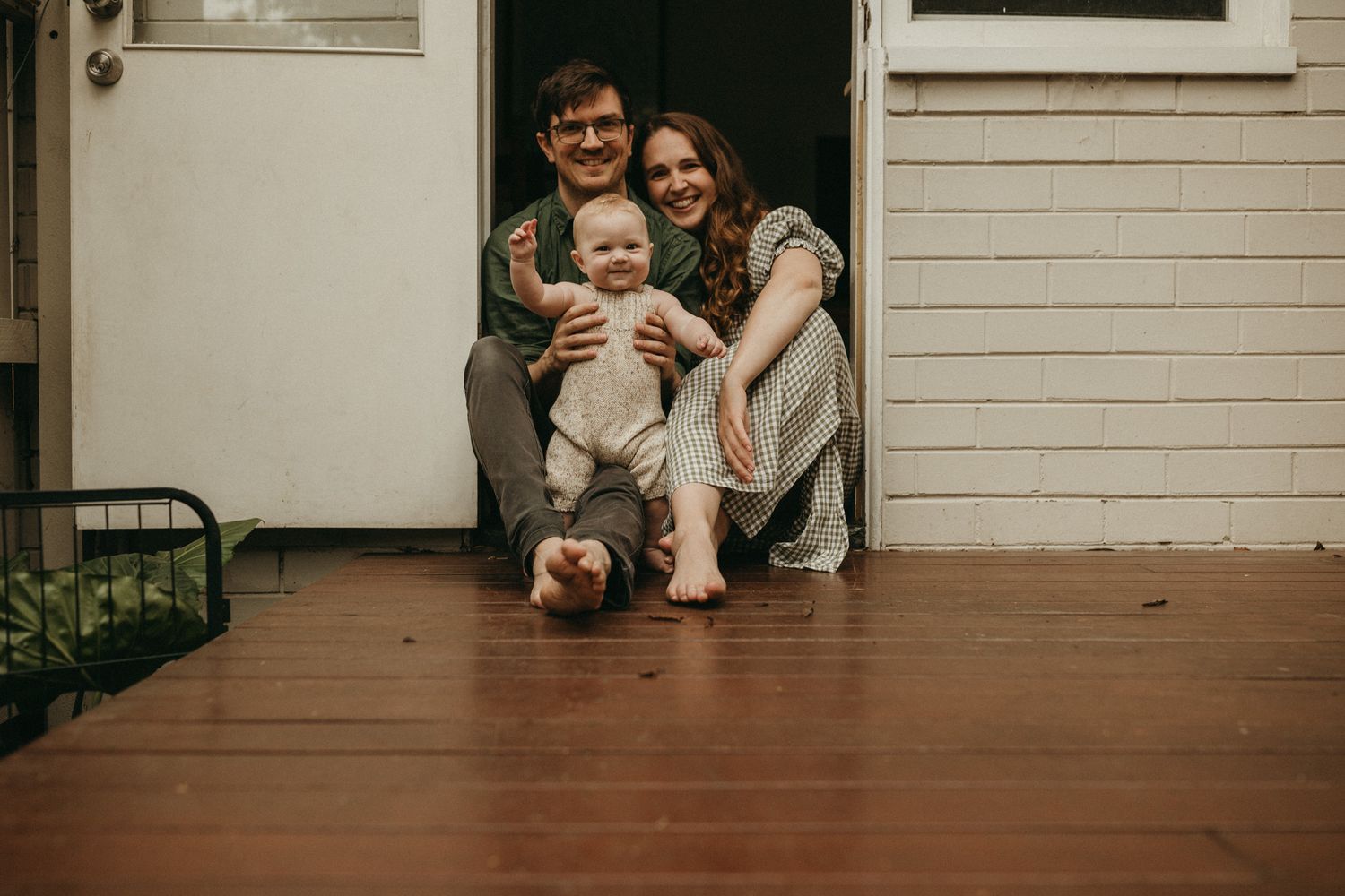 A heartwarming family moment captured on a wooden porch of a white house.