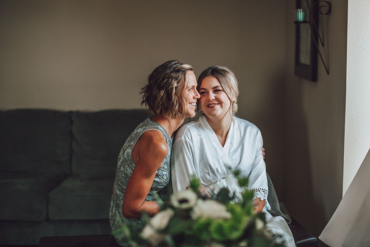 Wedding preparation scene with people in light-colored robes sharing an emotional moment.