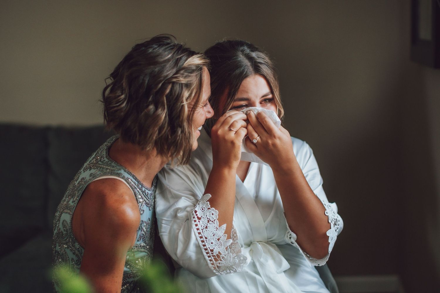 An intimate moment shared between wedding party members in a softly lit room.