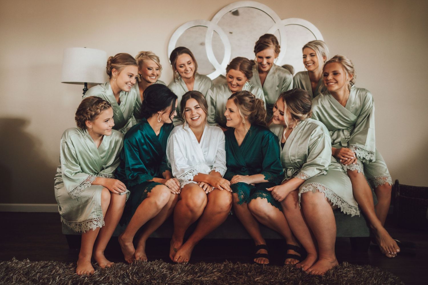 Wedding party members in matching robes pose together on a couch.