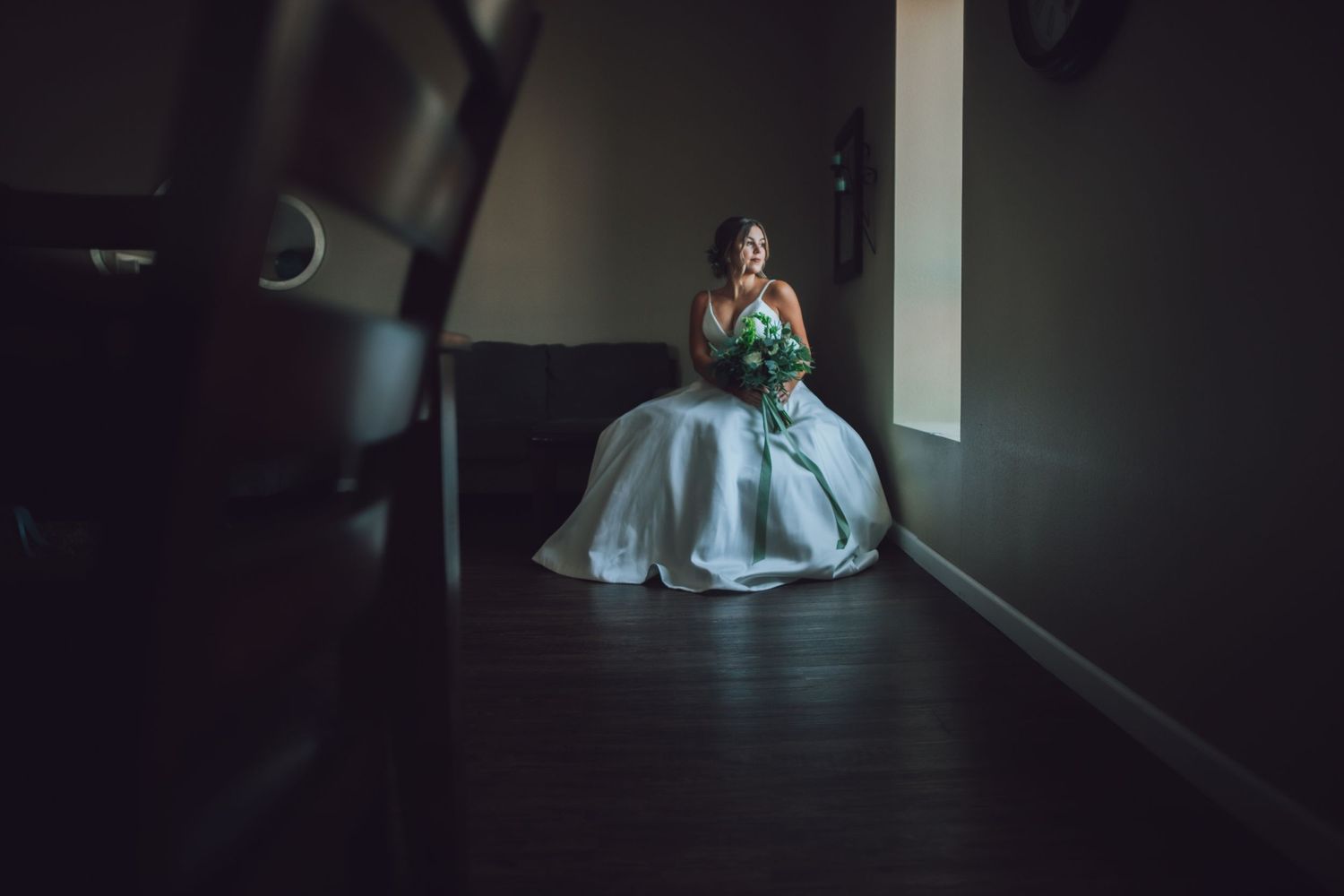 Dramatic moody wedding portrait with a white dress and dark shadows creating an intimate atmosphere.