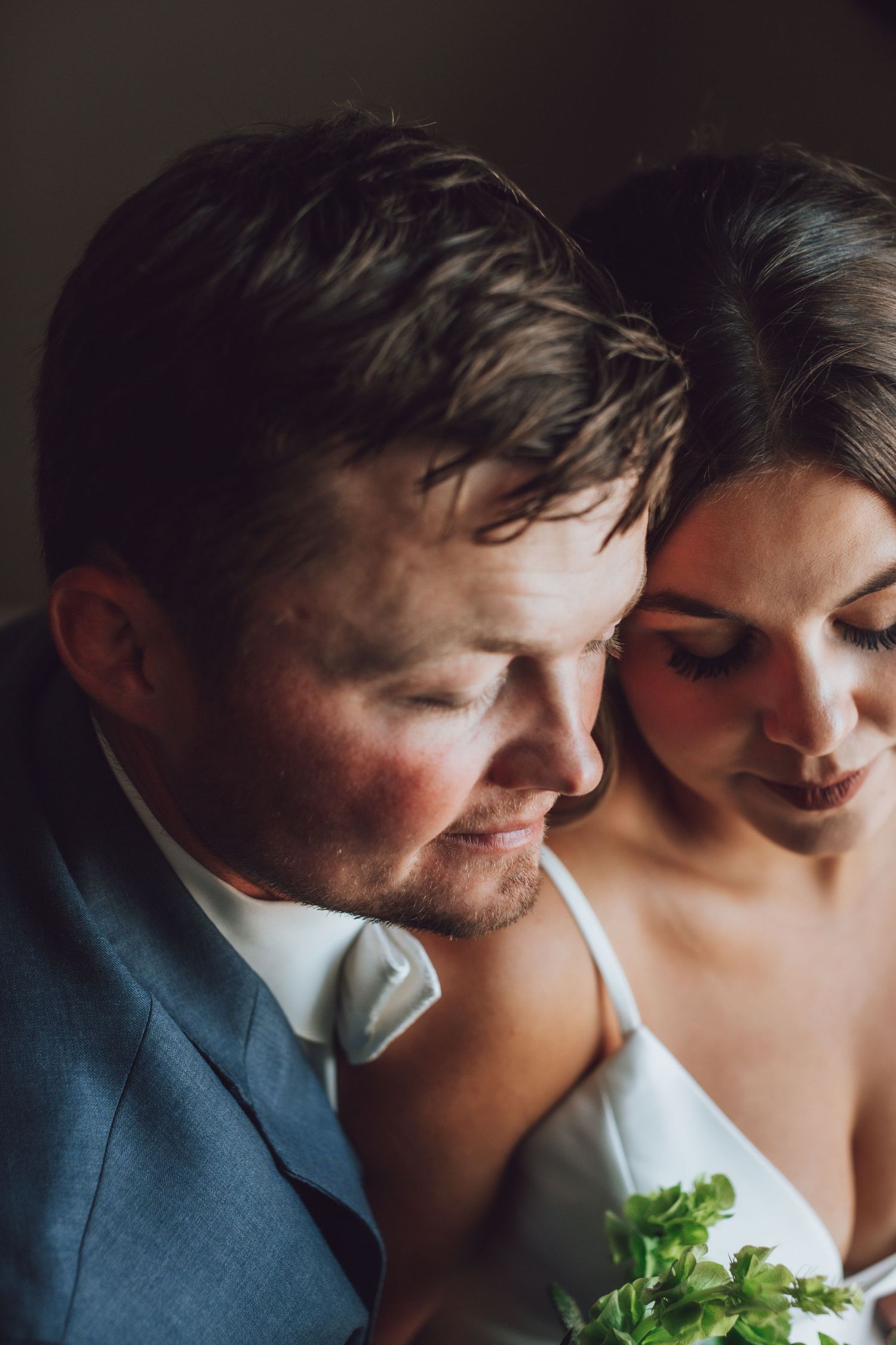 Romantic wedding couple shares intimate moment with soft lighting and floral details.
