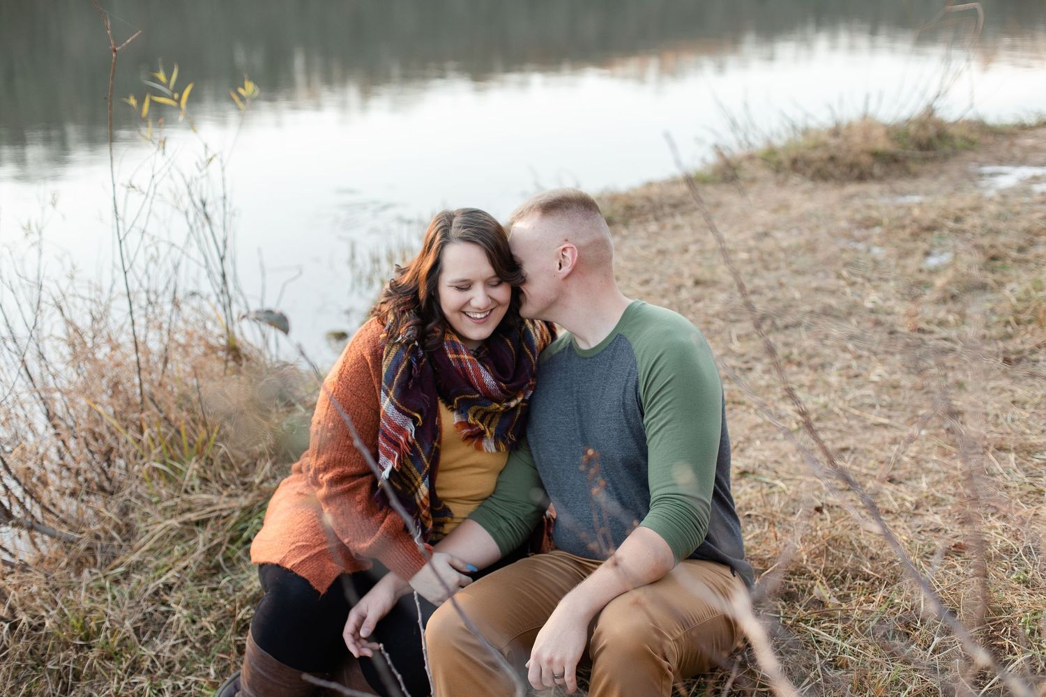 A romantic lakeside photoshoot featuring tender moments between a couple in casual attire.