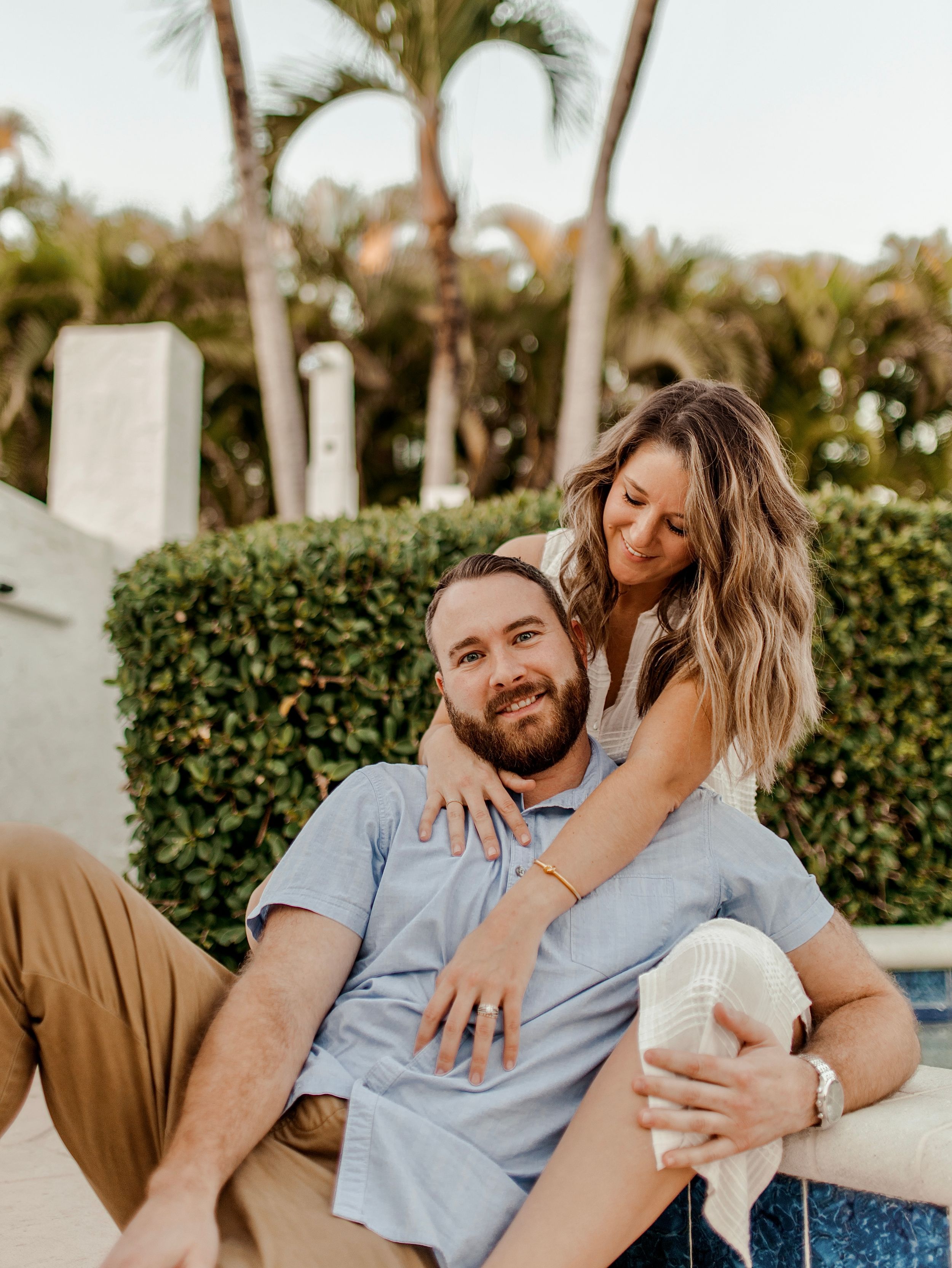 Couple relaxing outdoors sharing a tender moment among tropical landscaping.