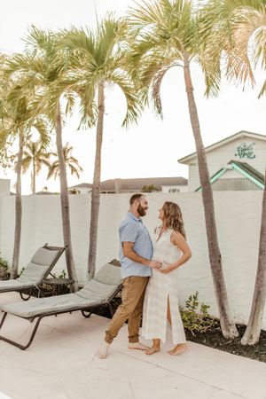 A couple shares an intimate moment on a resort patio surrounded by swaying palm trees.