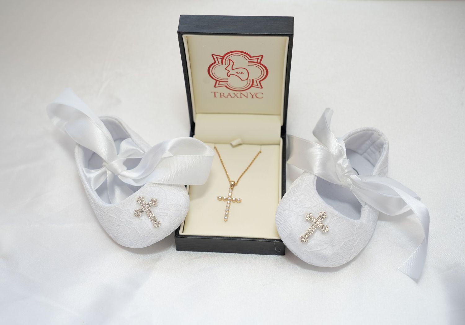 White baptismal shoes and jewelry displayed with decorative box.