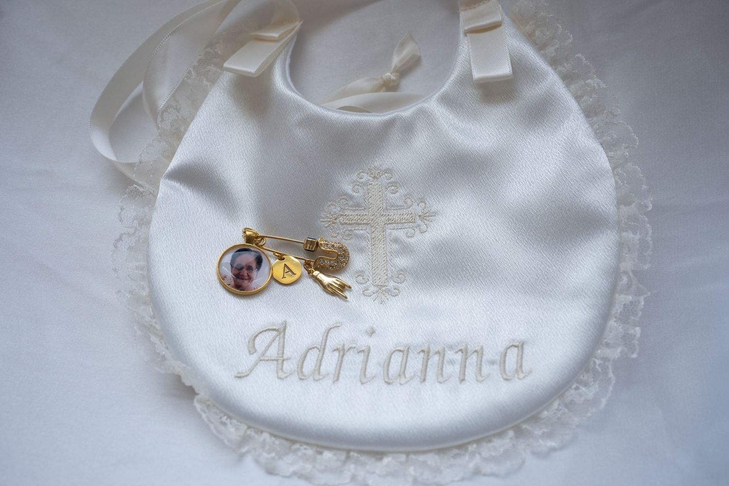 Personalized white baby bib with embroidered name and decorative details.