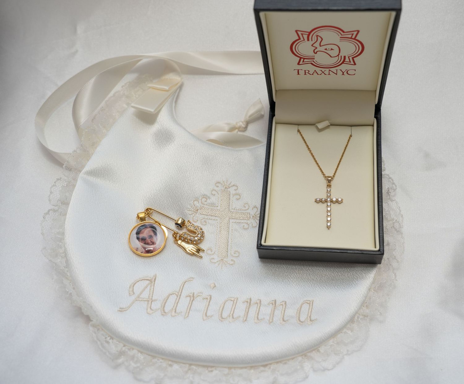 Elegant jewelry box displaying religious cross necklace and baby accessories.