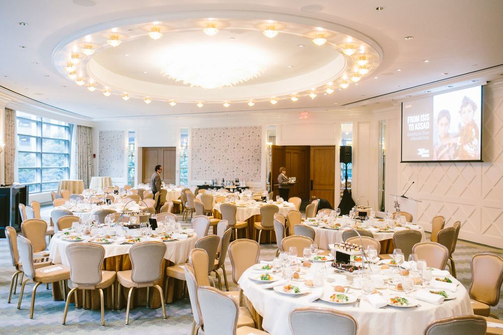 Elegant banquet hall with round tables, white linens, and dramatic circular ceiling with ambient lighting.