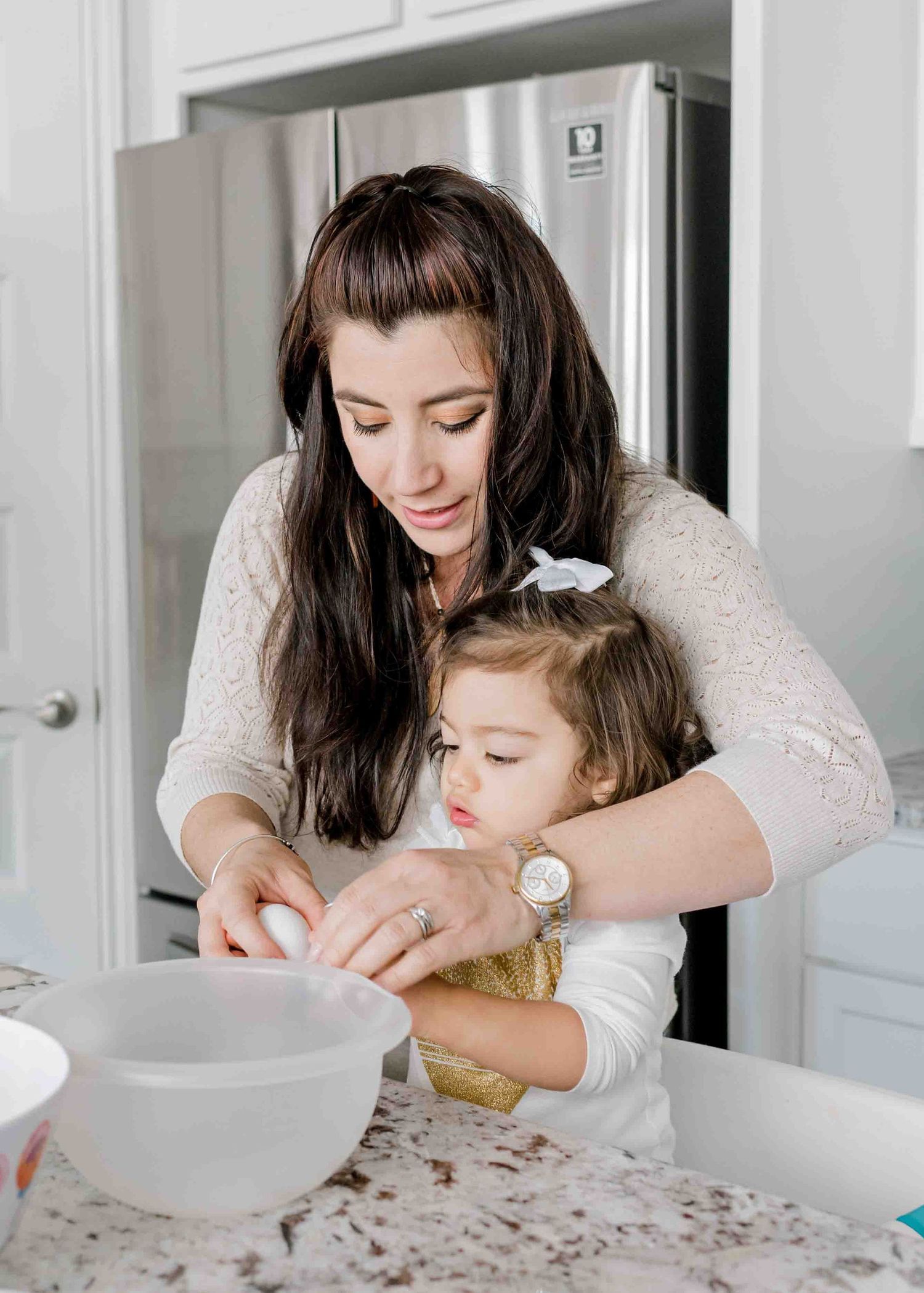A mother and child baking together at a granite kitchen counter.