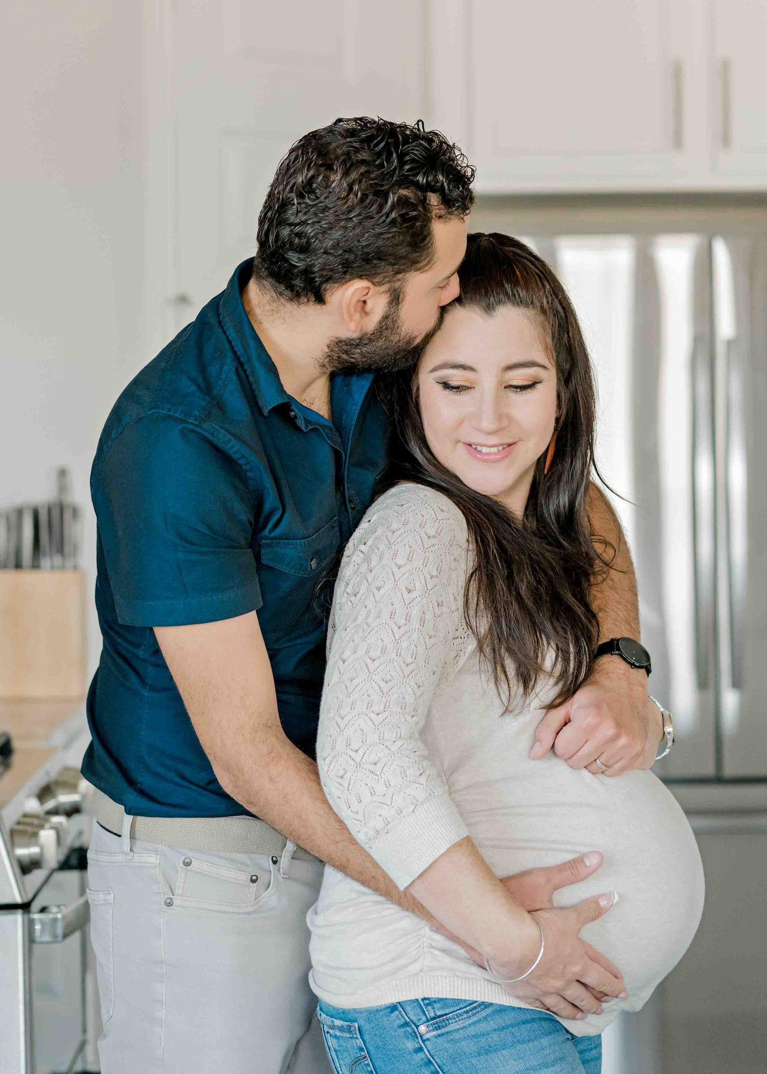 A tender moment captured between a couple in a bright modern kitchen setting.