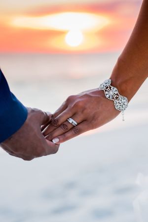 groom holding brides hand at sunset on their beach wedding day on Panama City Beach Florida