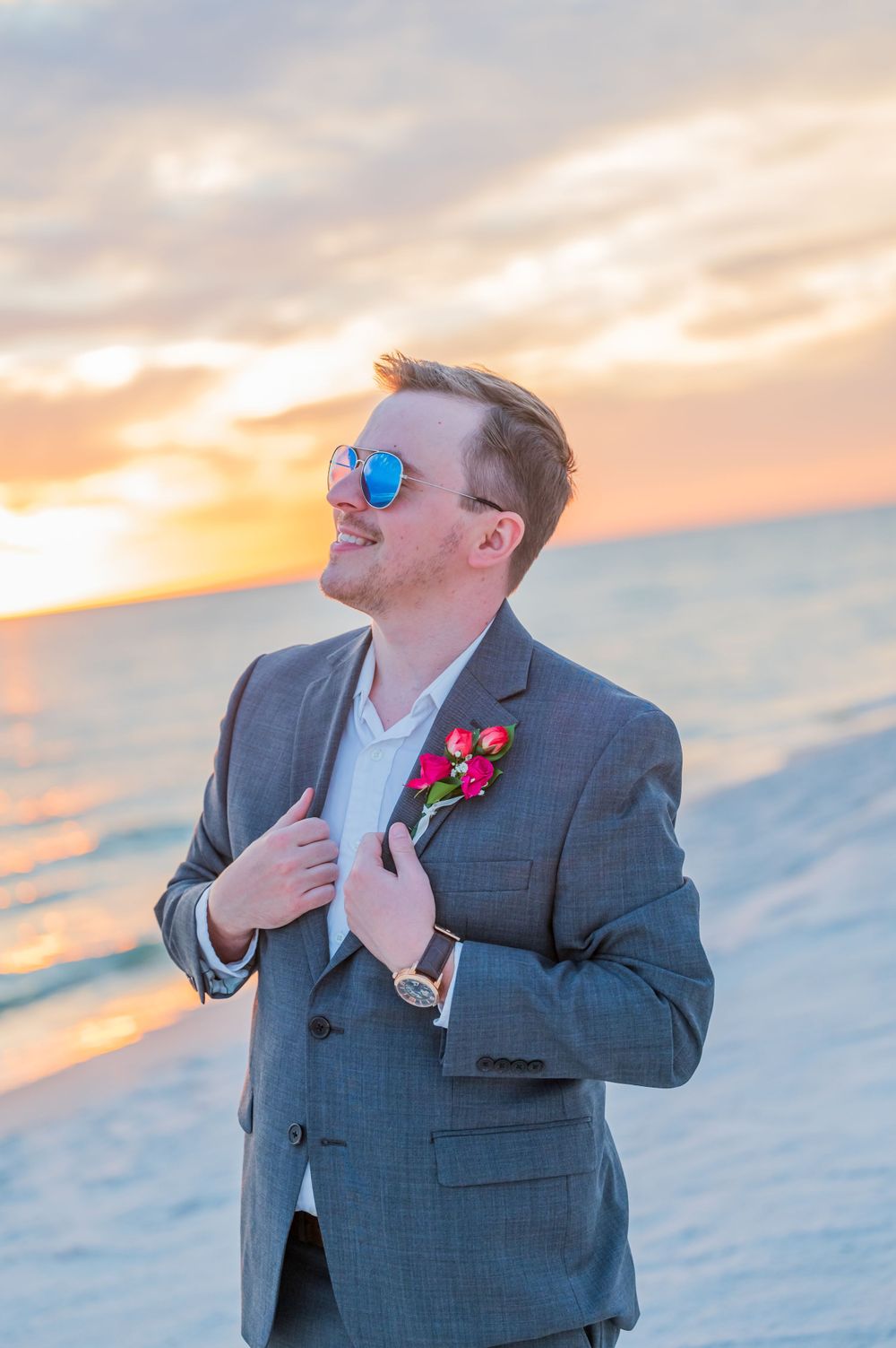 groom posing with sunglasses on his beach wedding day at sunset on Panama City Beach florida