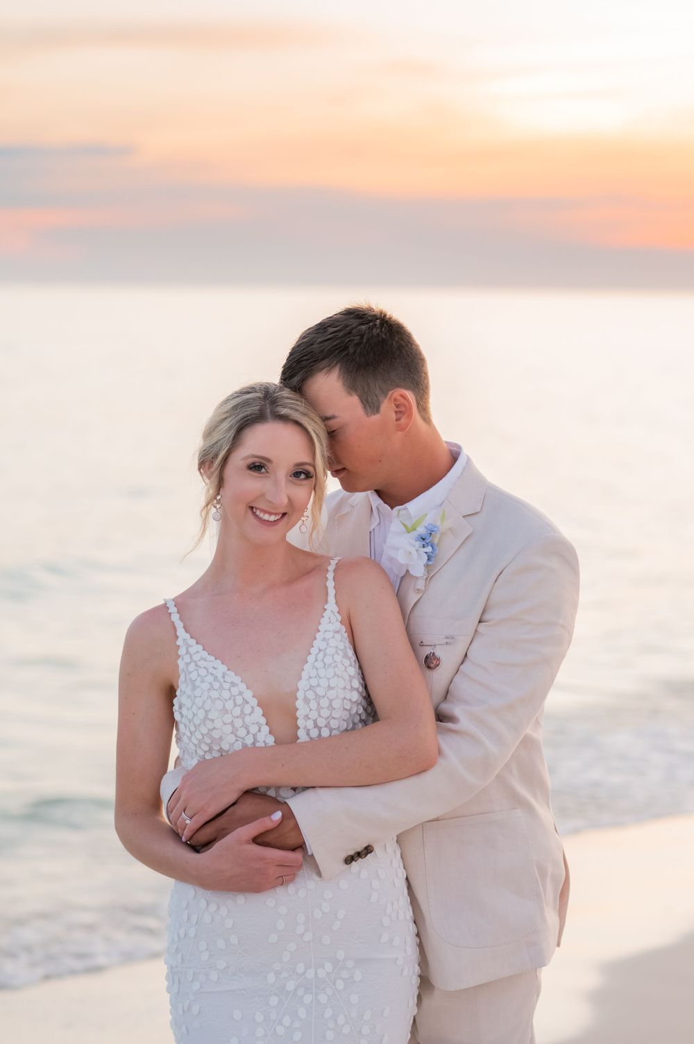 groom holding bride on the beach on their wedding day at sunset on Panama City Beach Florida