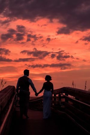 bride & groom walking into sunset on pier after their beach wedding on Panama City Beach Florida