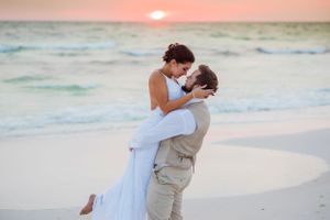 Groom picking up bride on their beach wedding day at sunset on Panama City Beach Florida