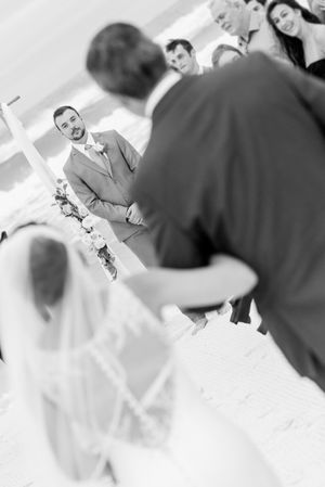 grrom seeing bride as she walks down the aisle on their beach wedding day on Panama City Beach Florida at sunset