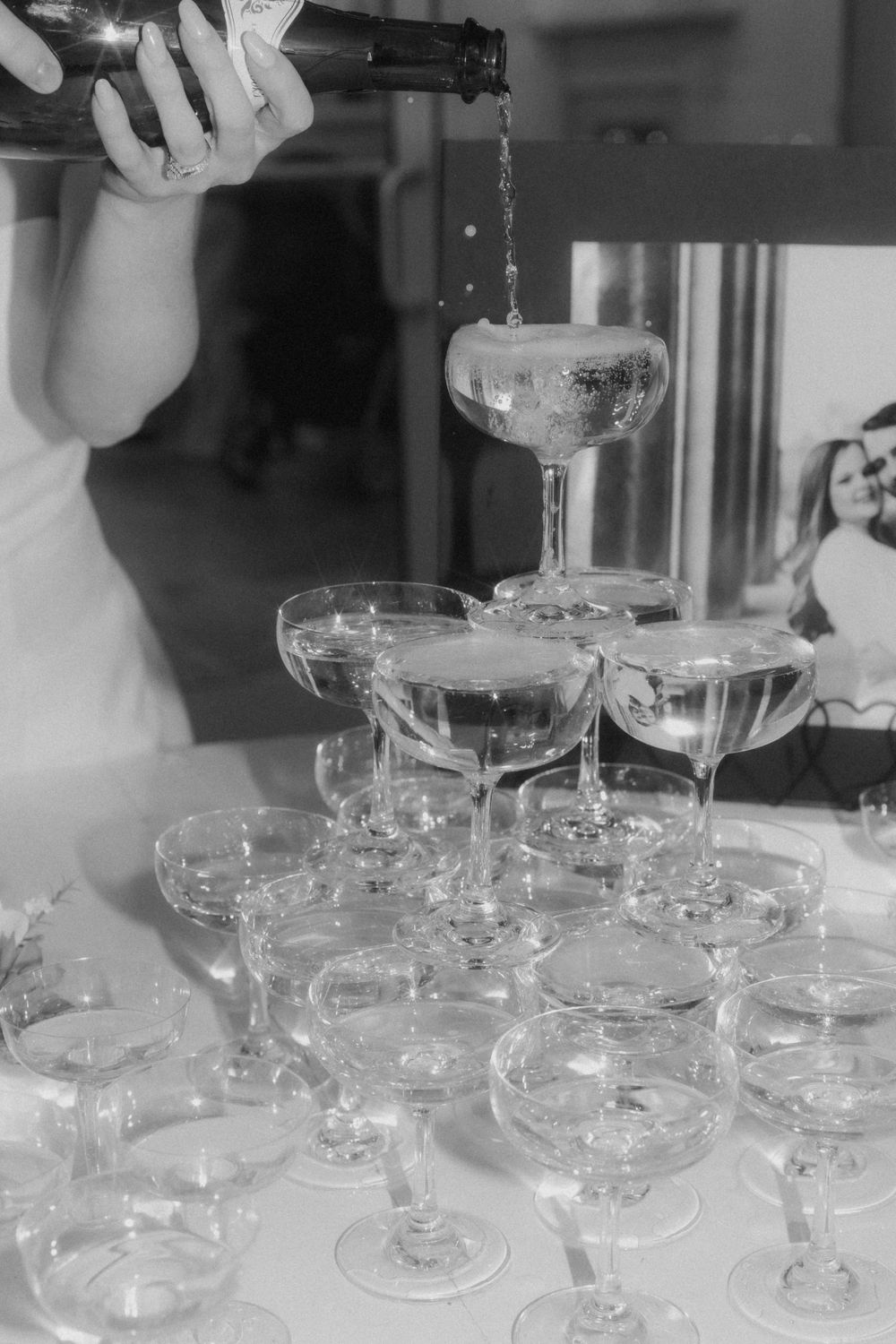 Champagne being poured into a tower of vintage coupe glasses at an elegant event.