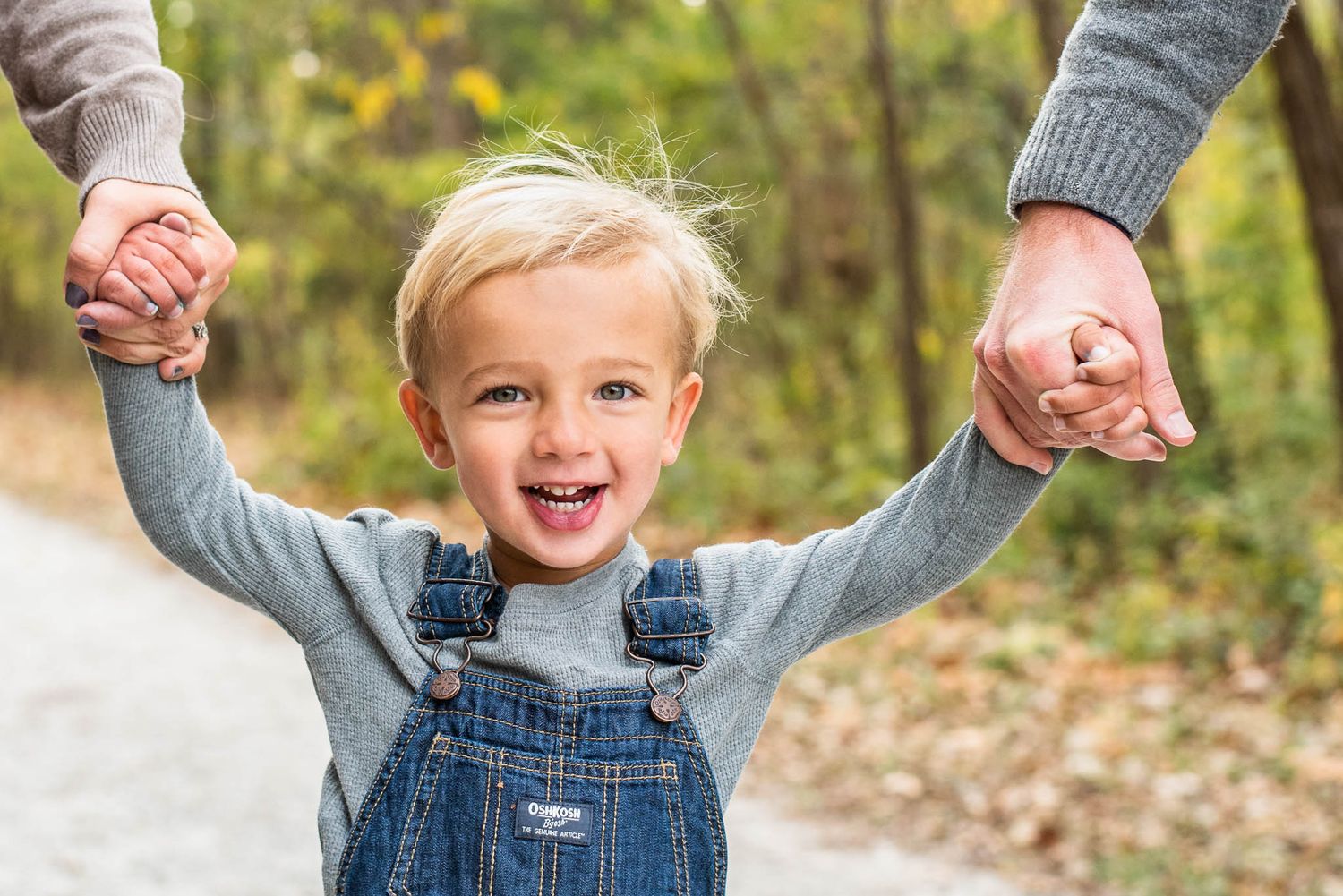 Little boy holding hands with his mom and dad as they walk